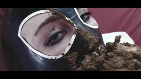 Brunette in gas mask jerks off on red bedsheet with substance play