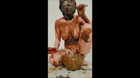 Slim brunette covered in mud eating it off her body