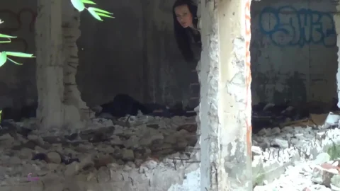 Brunette in slim body walks through abandoned building filmed in dayli