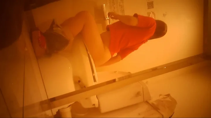 Brunette in bathroom adjusting clothes after using toilet